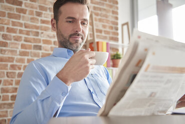 Man reading newspaper drinking coffee - ISF04794