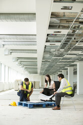 Drei Personen sitzen in einem neu errichteten Büroraum und betrachten Baupläne - ISF04845
