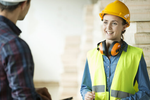 Zwei Menschen stehen auf einer Baustelle, tragen Schutzhelme und führen eine Diskussion - ISF04846