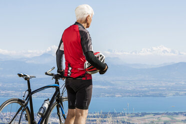 Älterer Mann in Radfahrerkleidung, auf einem Hügel stehend, neben einem Fahrrad, mit Blick auf die Aussicht, Genf, Schweiz, Europa - ISF04859