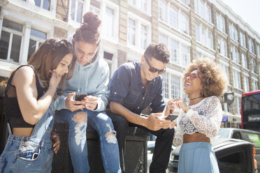 Vier junge Freunde im Freien, die auf ihr Smartphone schauen - ISF04867