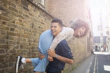 Young couple fooling around in street, man carrying woman over shoulder - ISF04872