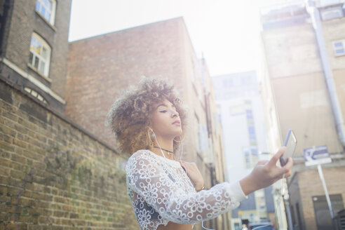 Junge Frau im Freien, die ein Selfie mit ihrem Smartphone macht, Blickwinkel niedrig - ISF04883