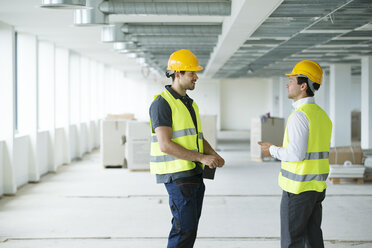 Two men wearing hi vis vest, having discussion in newly constructed office space - ISF04923