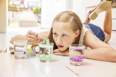 Girl lying on floor doing experiment with glasses of water - ISF04998