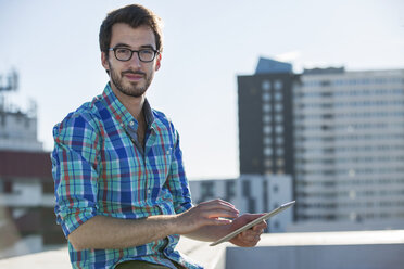 Porträt eines Mannes, der an einem Bürofenster steht und ein digitales Tablet benutzt - ISF05024