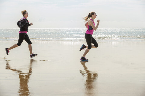 Mutter und Tochter laufen am Strand, Folkestone, UK, lizenzfreies Stockfoto