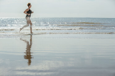 Woman running on beach, Folkestone, UK - ISF05060