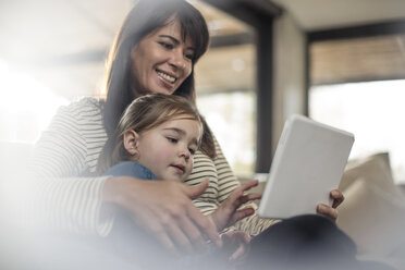 Frau mit Tochter auf dem Sofa mit Blick auf ein digitales Tablet - ISF05078