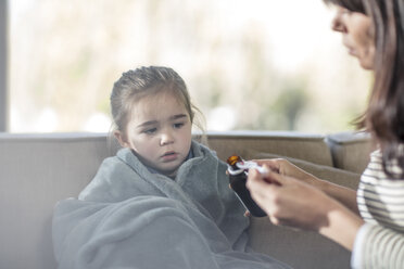 Mutter gießt Medizin für Tochter in Decke eingewickelt auf Sofa - ISF05085