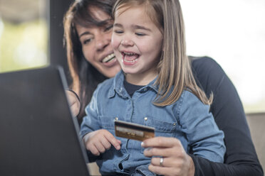 Mädchen und Mutter auf dem Sofa mit Laptop und Kreditkarte zum Online-Shopping - ISF05089