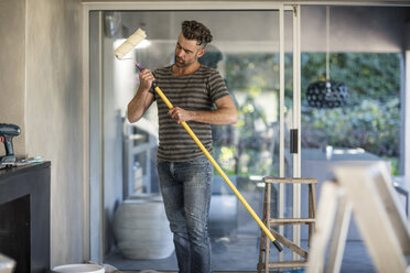 Mann in unmöblierter Wohnung, mit Farbroller in der Hand - ISF05091