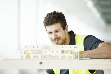 Man wearing hi vis vest, looking at model of building - ISF05102