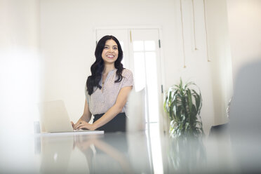 Young businesswoman typing on laptop at desk - ISF05141