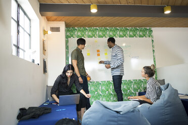 Young businessmen and women using laptop and whiteboard in creative meeting room - ISF05170