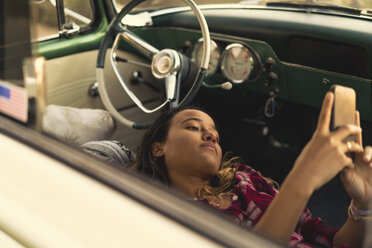 Junge Frau schaut auf ihr Smartphone vor einem Pickup in Newport Beach, Kalifornien, USA - ISF05210
