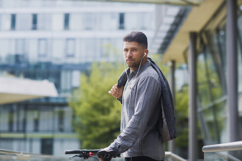 Mann mit Kopfhörern, der seine Jacke über der Schulter trägt und in die Kamera schaut - ISF05239