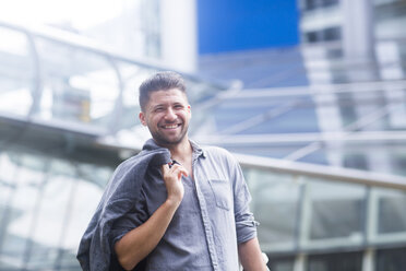 Portrait of man carrying jacket over shoulder looking at camera smiling - ISF05243