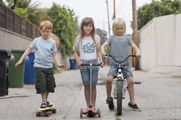 Mädchen und Jungen in der Gasse mit Motorroller, Fahrrad und Skateboard - ISF05269