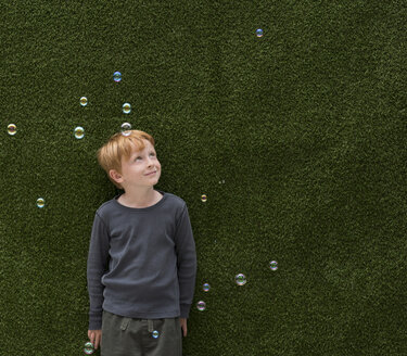 Junge vor Kunstrasen lächelt Blasen an - ISF05280