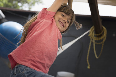 Girl hanging on monkey bar looking down at camera smiling - ISF05281