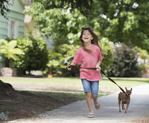 Girl walking dog in street - ISF05289