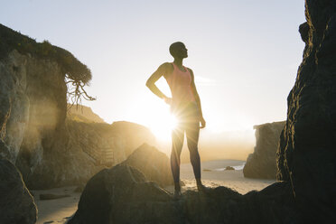 Young woman standing on rocks on beach, looking at view - ISF05316