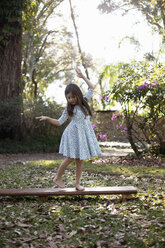 Mädchen balanciert auf einer Holzstufe im schattigen Garten - ISF05464