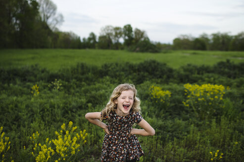 Porträt eines Mädchens mit gewelltem blondem Haar, das auf einem Feld lacht - ISF05467