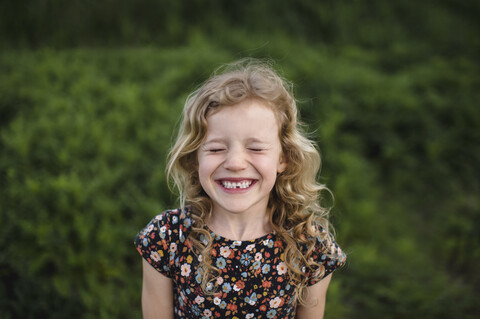 Portrait of girl with wavy blond hair and missing tooth in field stock photo