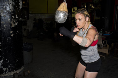Weiblicher Boxer trainiert im Fitnessstudio, schlägt Punchingball - ISF05480