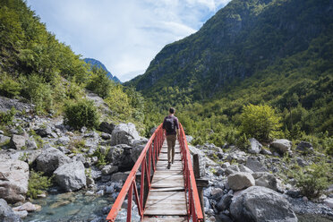 Rückansicht eines Mannes beim Überqueren einer Brücke, Verfluchte Berge, Theth, Shkoder, Albanien, Europa - ISF05520