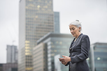 Businesswoman using mobile phone, Canary Wharf, London, UK - ISF05597