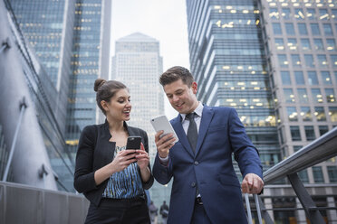 Businessman and businesswoman using mobile phone, Canary Wharf, London, UK - ISF05606