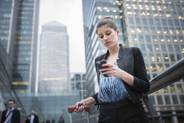 Blonde business woman checking smartphone on city rooftop stock photo