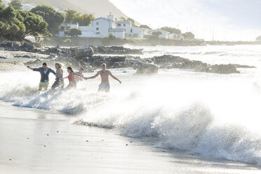 Young adult friends running and splashing through waves at beach party - ISF05688