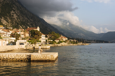 Junger Mann steht am Pier und schaut weg, Kotor, Montenegro, Europa, lizenzfreies Stockfoto