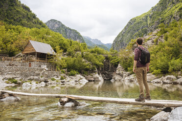 Man on wooden bridge looking at cabin, Accursed mountains, Theth, Shkoder, Albania, Europe - ISF05700