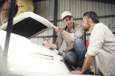 Two men checking boat bodywork in repair workshop - ISF05765