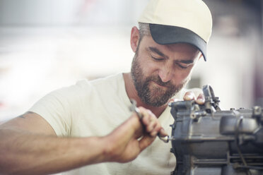 Mann bei der Reparatur eines Außenbordmotors in einer Bootsreparaturwerkstatt - ISF05770