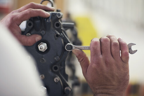 Nahaufnahme von männlichen Händen, die einen Außenbordmotor in einer Bootsreparaturwerkstatt reparieren - ISF05771