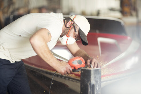 Man sanding bodywork in boat repair workshop - ISF05778