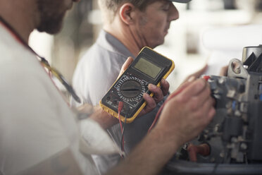 Man using machine to test outboard motor in boat repair workshop - ISF05780