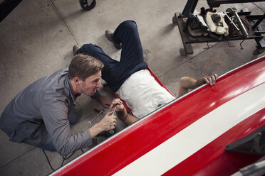 Overhead view of two men repairing in boat repair workshop - ISF05781