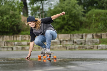 Junge Frau balanciert auf einem Skateboard - STSF01580