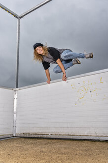 Porträt einer jungen Frau, die über eine Barriere springt - STSF01581