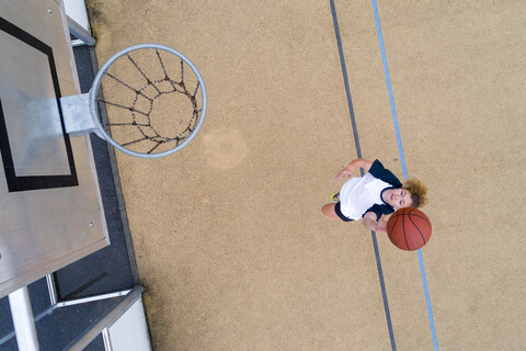 Junge Frau spielt Basketball, Ansicht von oben, lizenzfreies Stockfoto