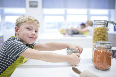 Ein glücklicher junger Schüler lernt mit einem breiten Lächeln im Gesicht kulinarische Fähigkeiten in einem Kochkurs. - WESTF24075