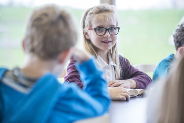 Eine Gruppe glücklicher Schulkinder, darunter ein lächelndes Mädchen, stellt sich für ein Foto in ihrem Klassenzimmer auf. - WESTF24081