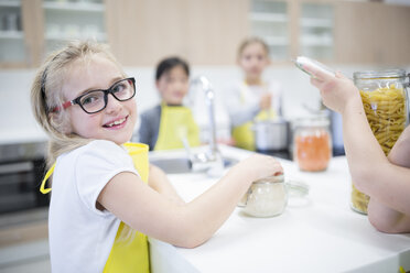 Eine Gruppe von Schulmädchen posiert während eines Kochkurses fröhlich für ein Foto, wobei ein Mädchen strahlend in die Kamera lächelt. - WESTF24089